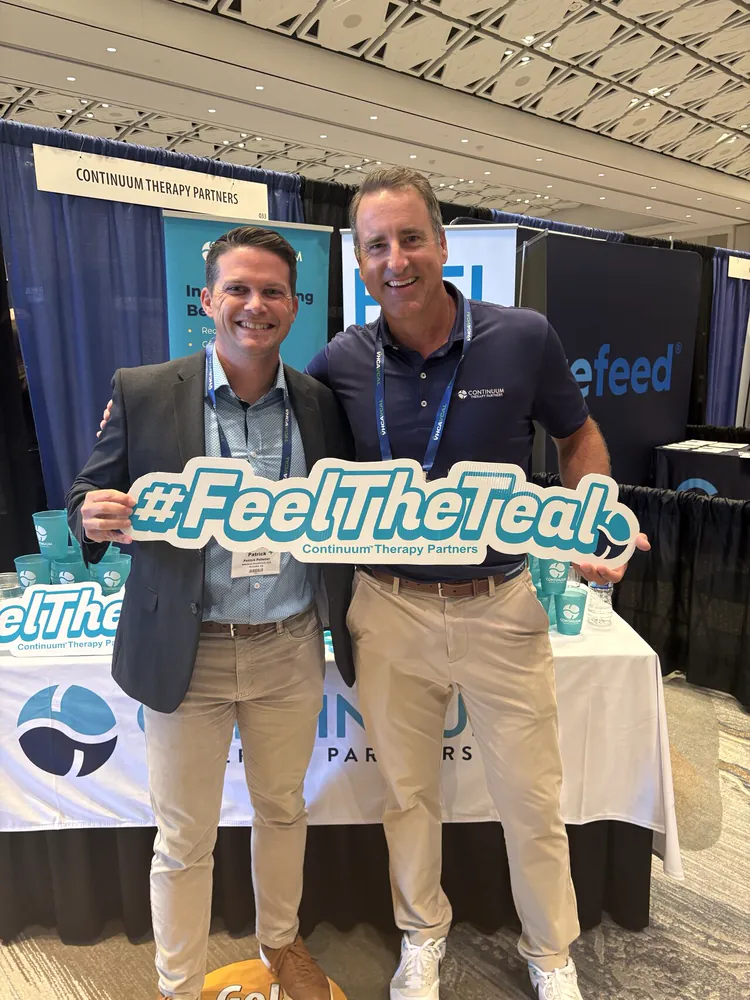 Two Continuum team members with the #FeelTheTeal sign at a conference