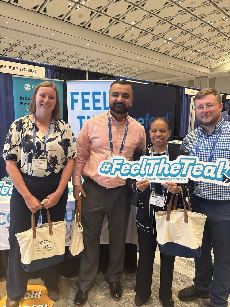 Conference visitors with Continuum tote bags and the #FeelTheTeal sign