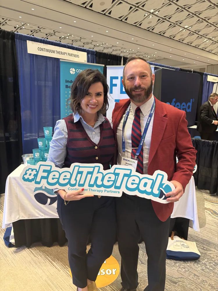 Two conference guests with the #FeelTheTeal sign