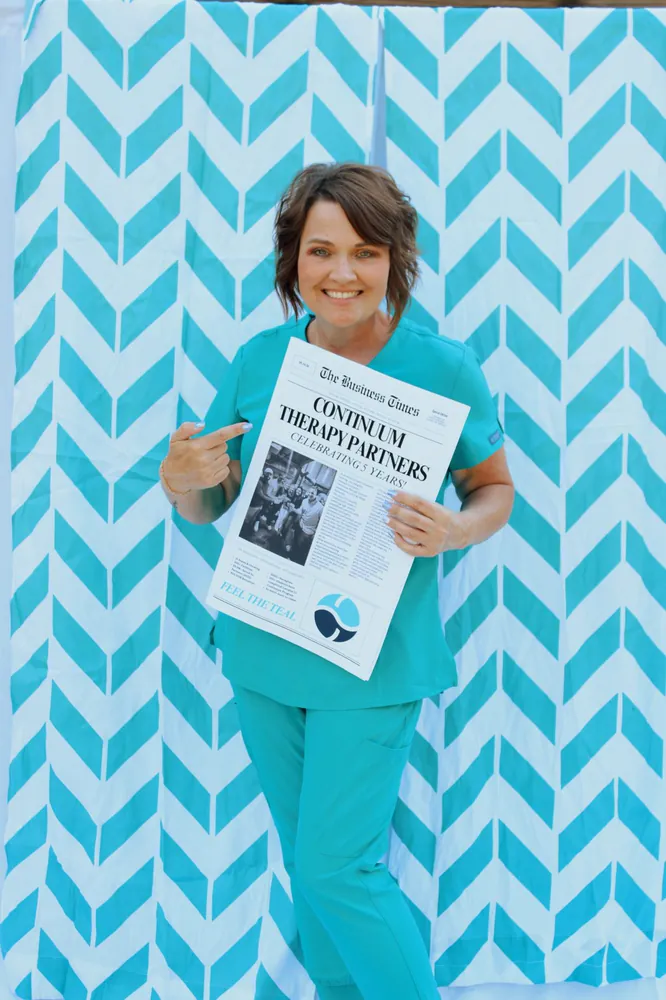 A Continuum therapist holding the five-year anniversary newspaper
